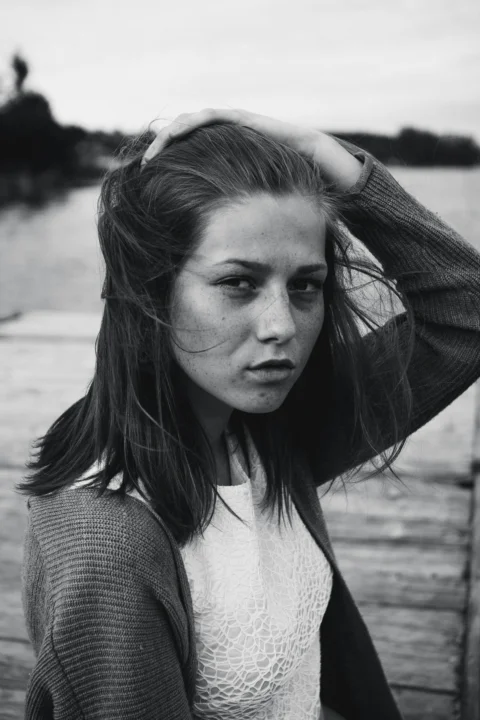 A woman standing on a dock with her hair blowing in the wind