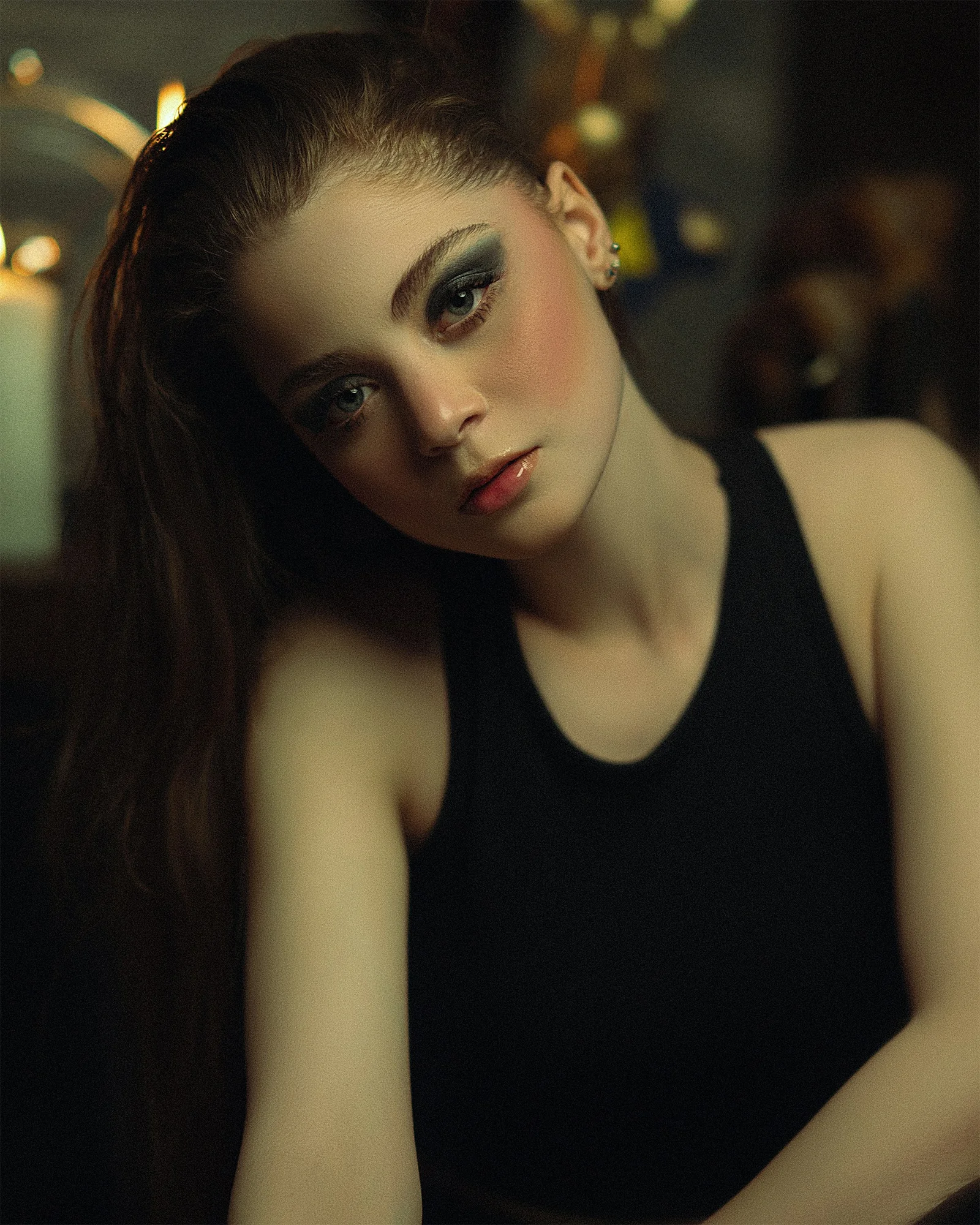 a woman in a black tank top with a candle in the background