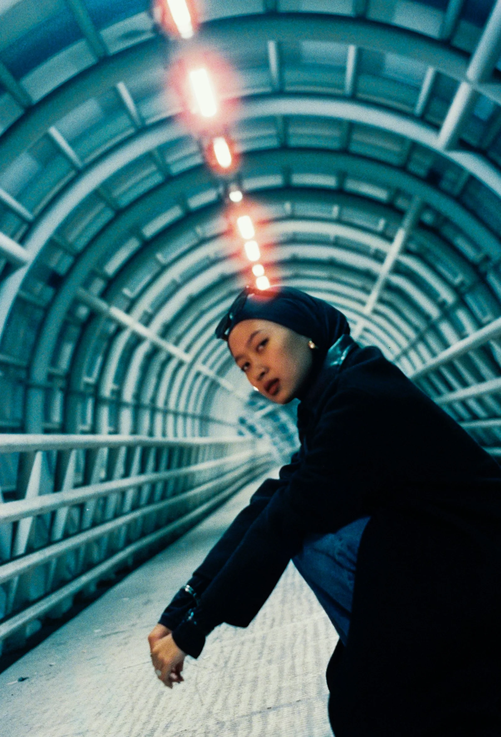 A woman crouches in a blue tunnel
