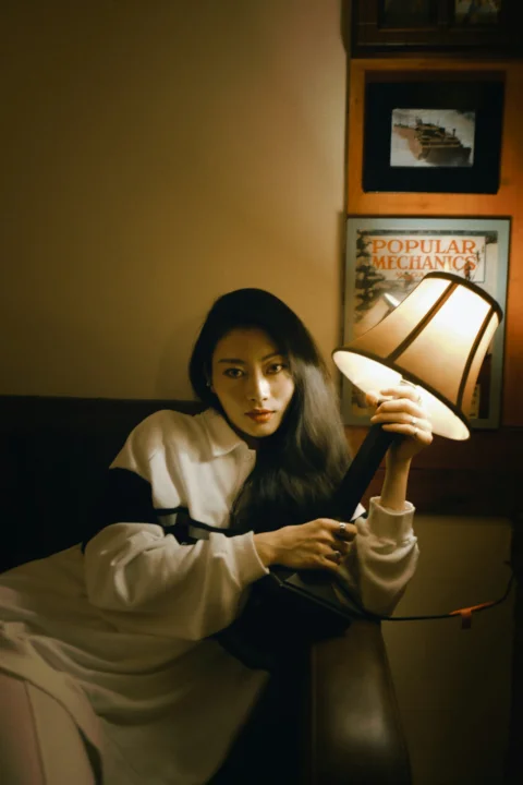 身穿白色长袖衬衫坐在床上的女子