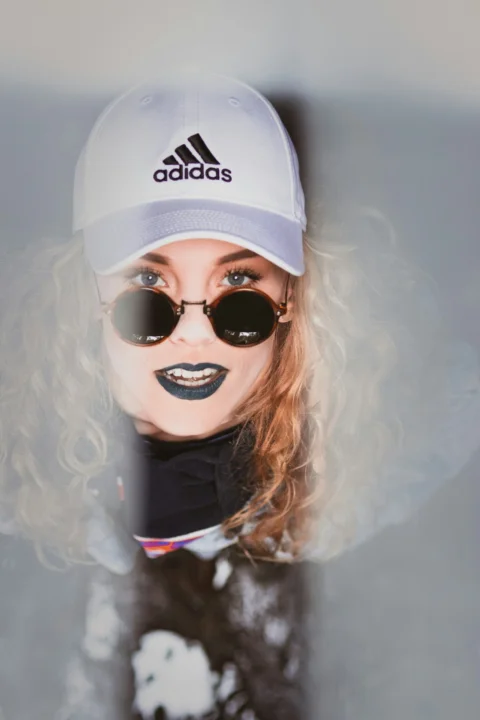 穿黑色連帽衫、戴白色 adidas 平沿帽的女子