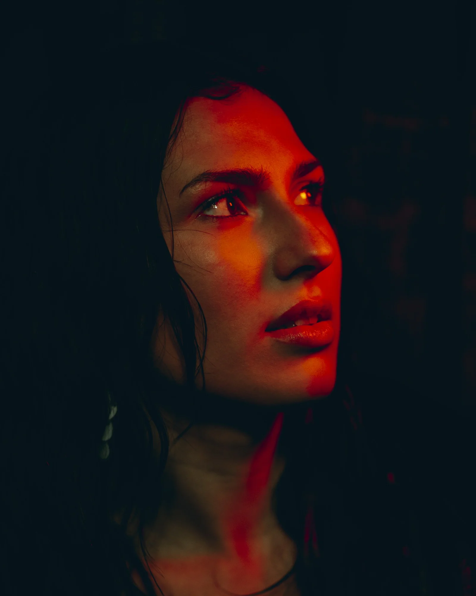 Woman with red lighting stares into the distance