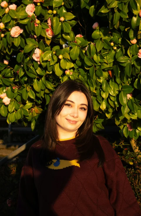Young woman in a sweater by a flowering bush