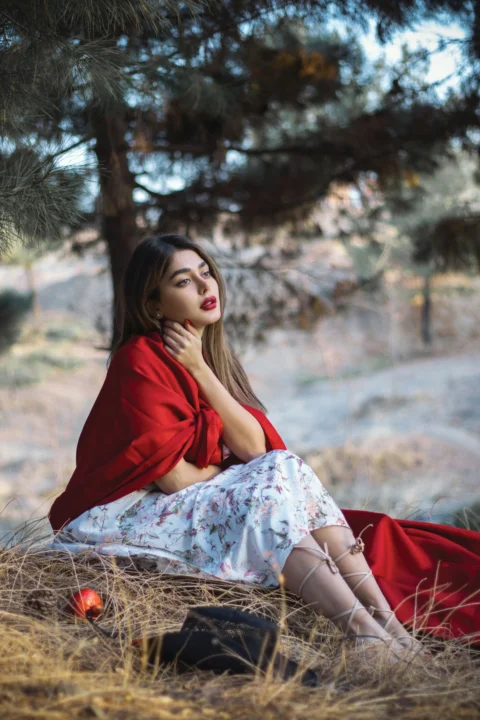 a woman in a red jacket is sitting in the grass