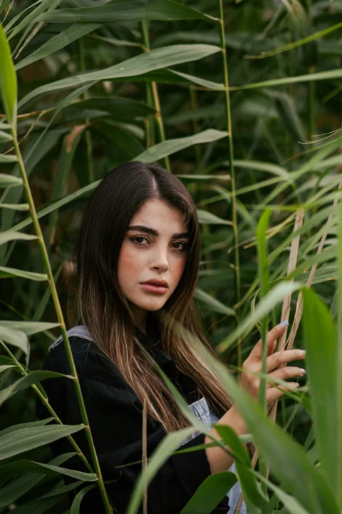 Young woman peeking through tall green reeds
