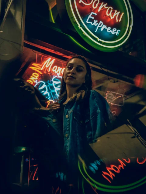 a woman standing in front of a neon sign