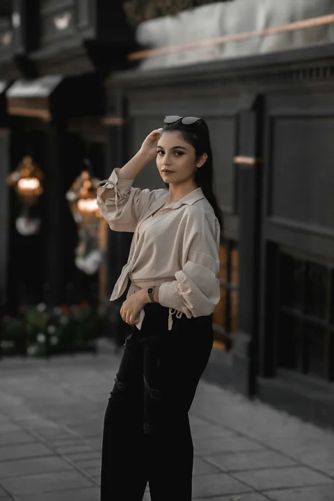 A woman standing on a sidewalk wearing black pants