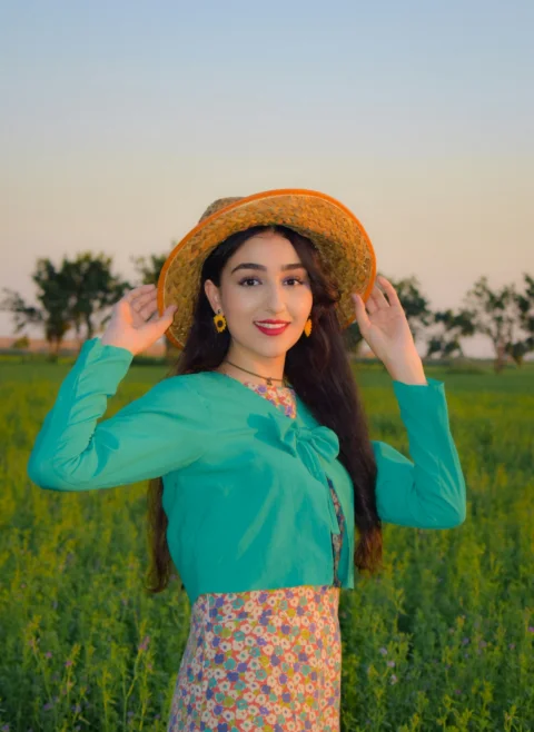 a woman wearing a hat standing in a field