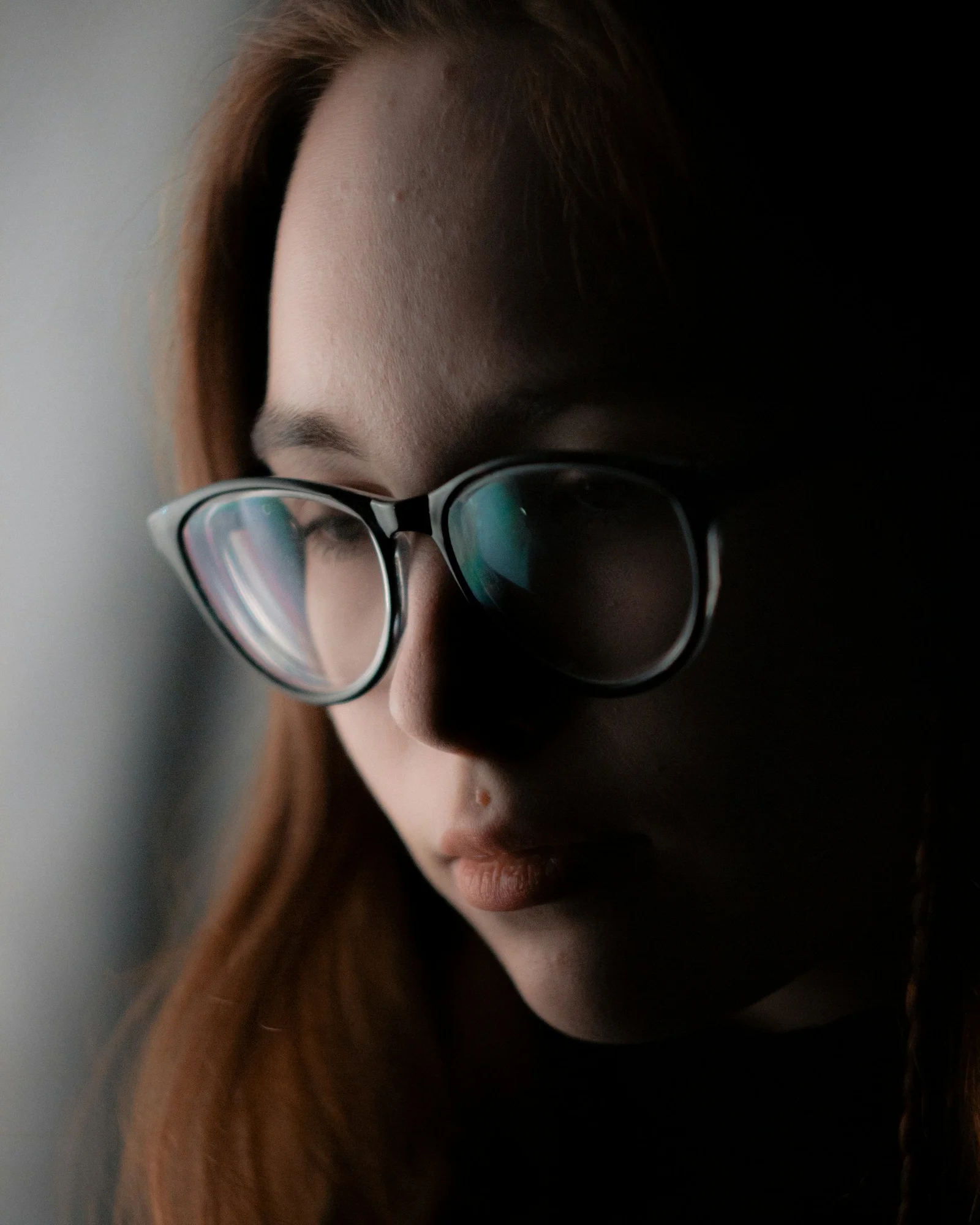 A woman wearing glasses looking down at her cell phone