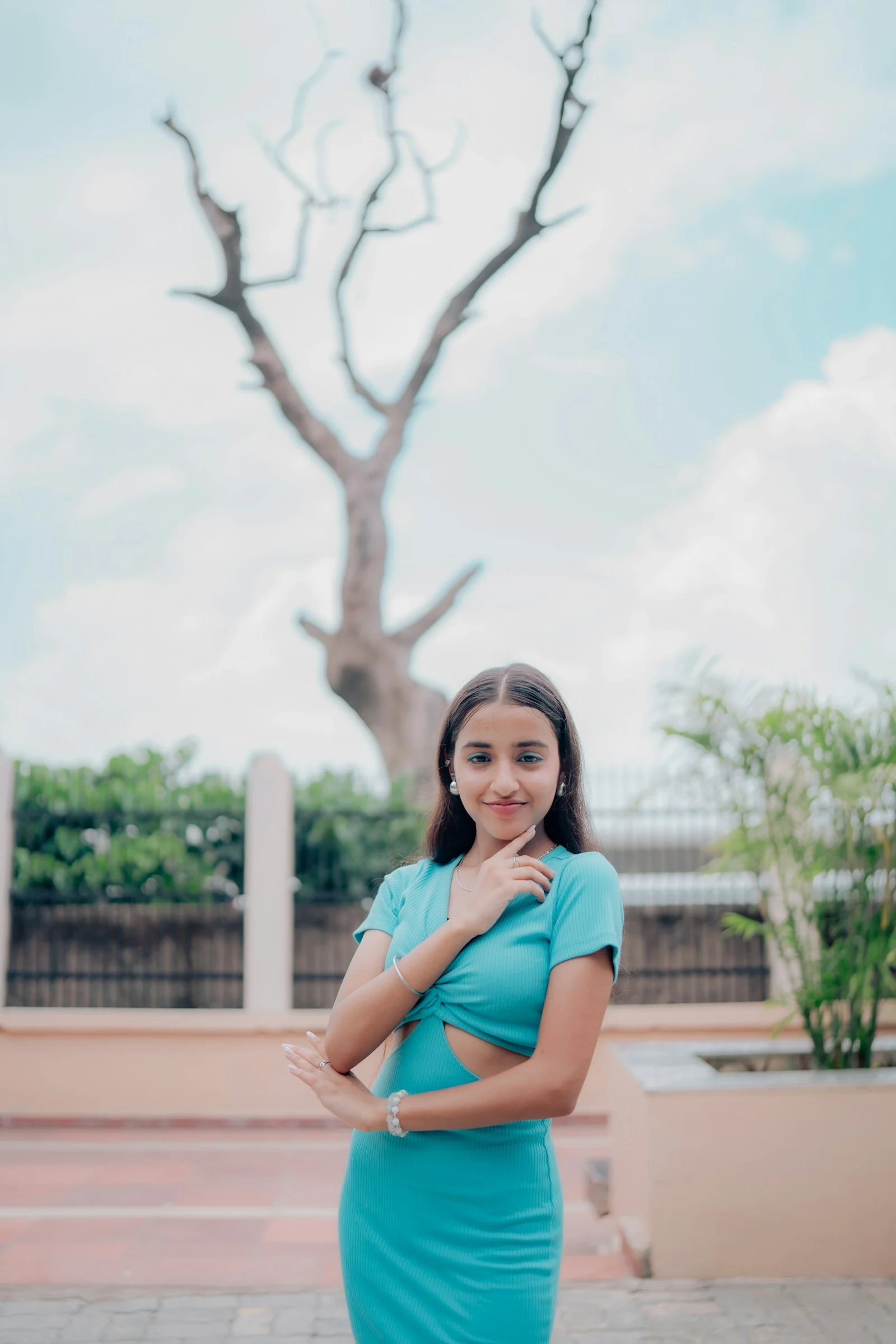 A young woman in a blue dress smiles outdoors
