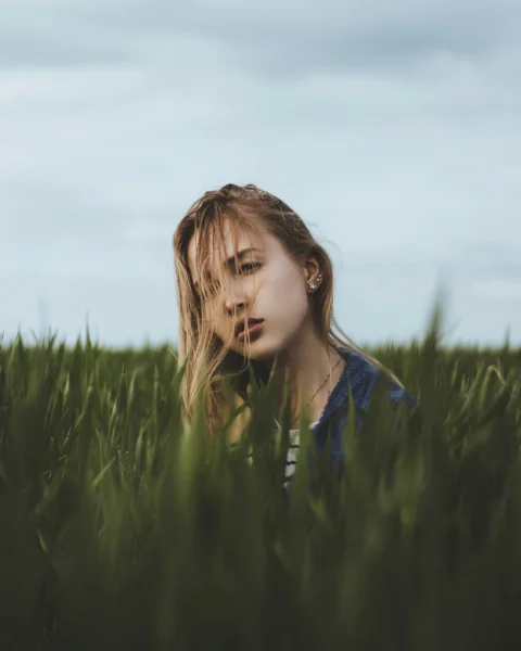 girl in blue jacket standing on green grass field during daytime
