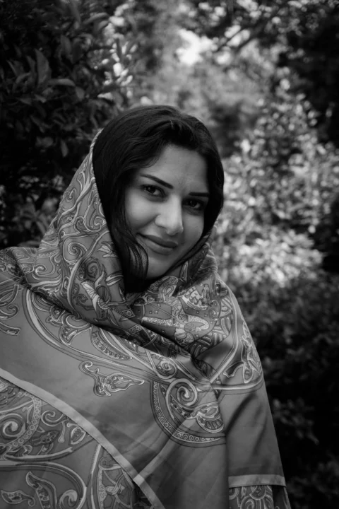 A woman in a patterned headscarf smiling in nature