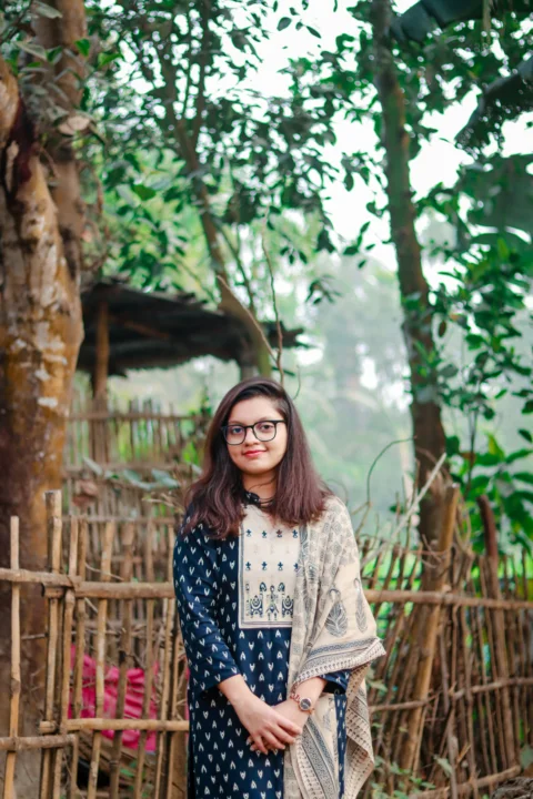 Young woman standing outdoors near a wooden fence