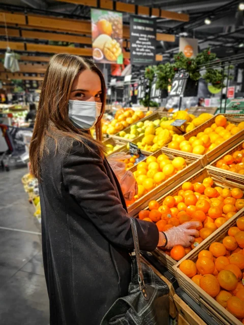 woman in black leather jacket standing in front of orange fruits