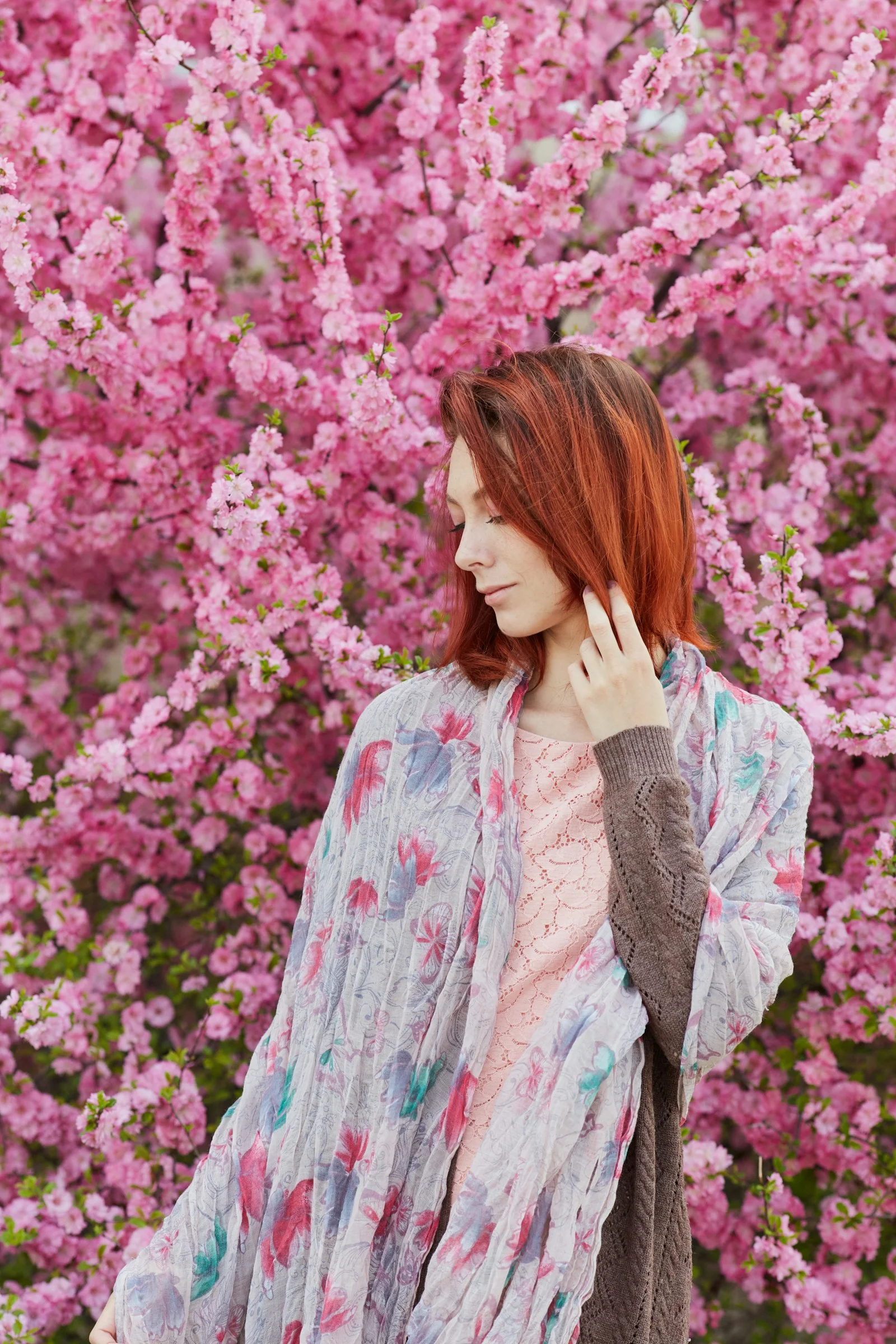 woman in white and blue long sleeve shirt standing near pink flowers