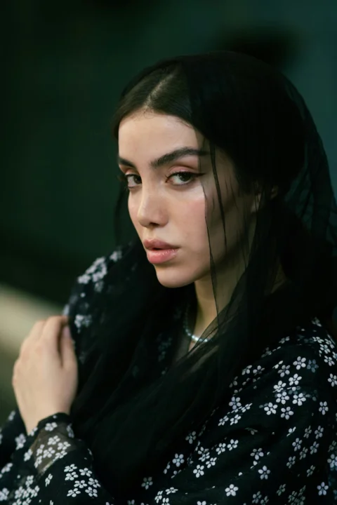 A woman gazes thoughtfully while wearing a veil