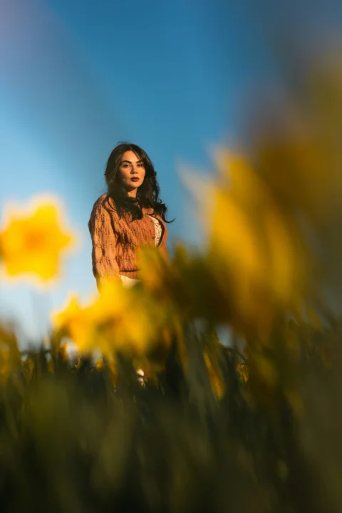 Woman poses among vibrant yellow daffodils