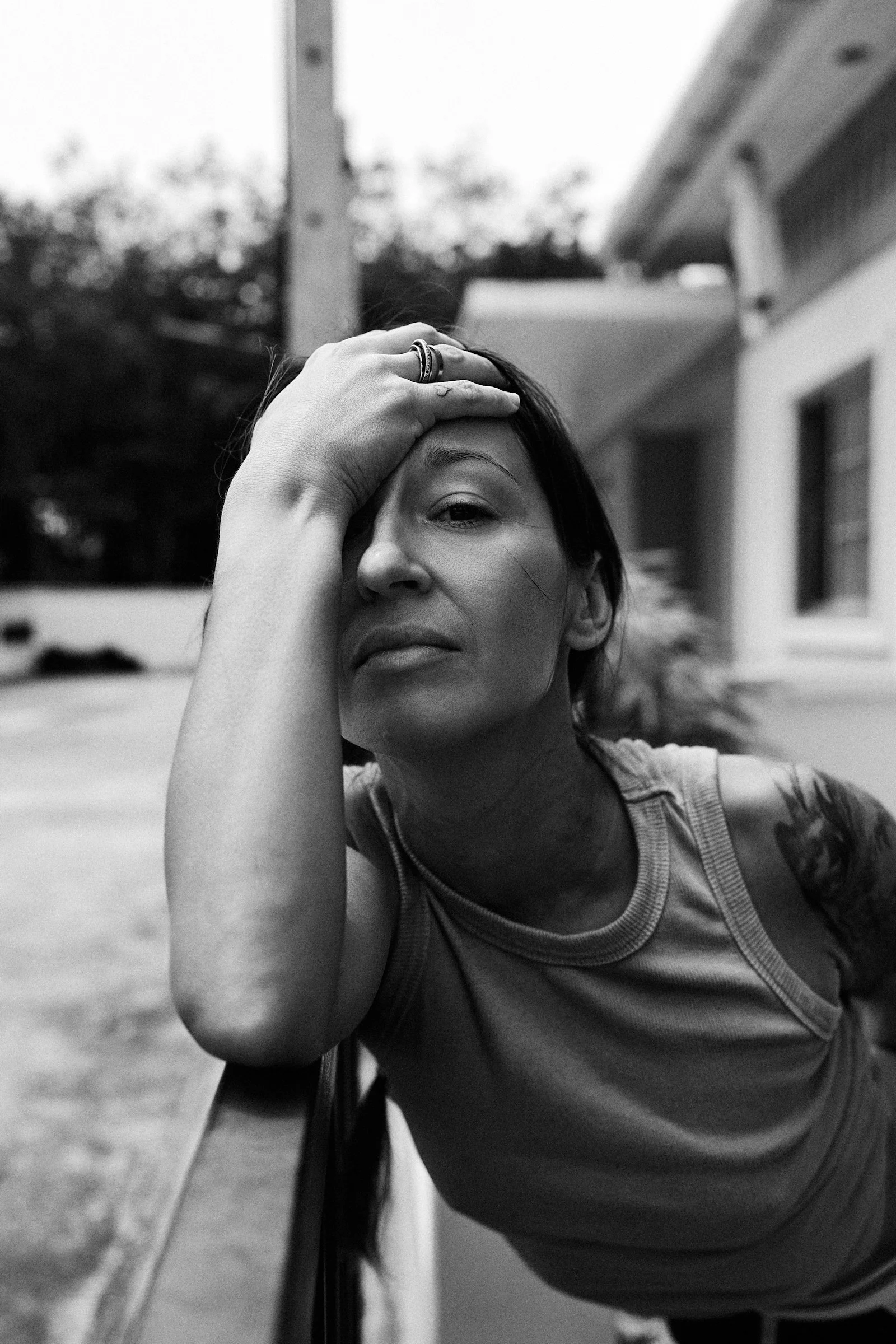 Woman rests her arm on a railing, looking serious