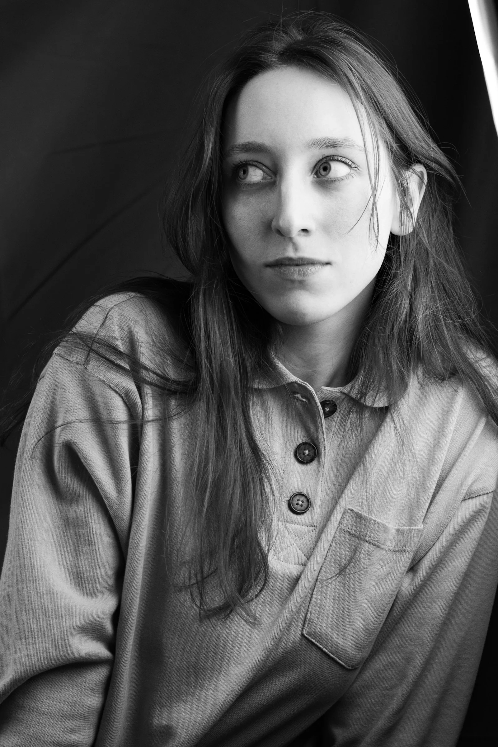 A woman stares off-camera with a thoughtful expression