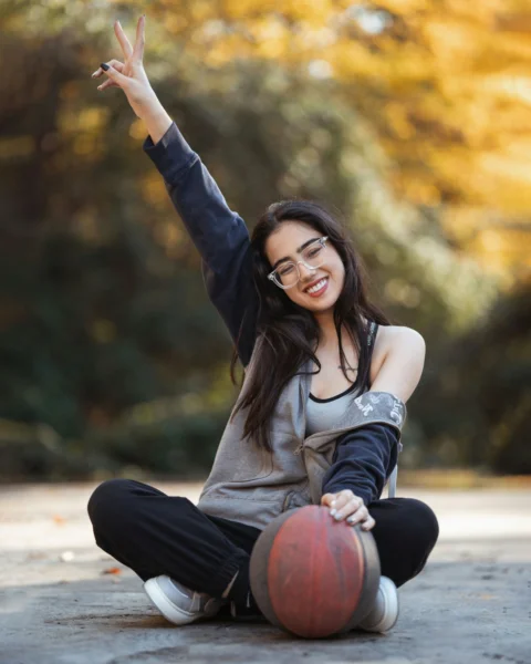 面帶微笑的女性在戶外拿著籃球擺出姿勢
