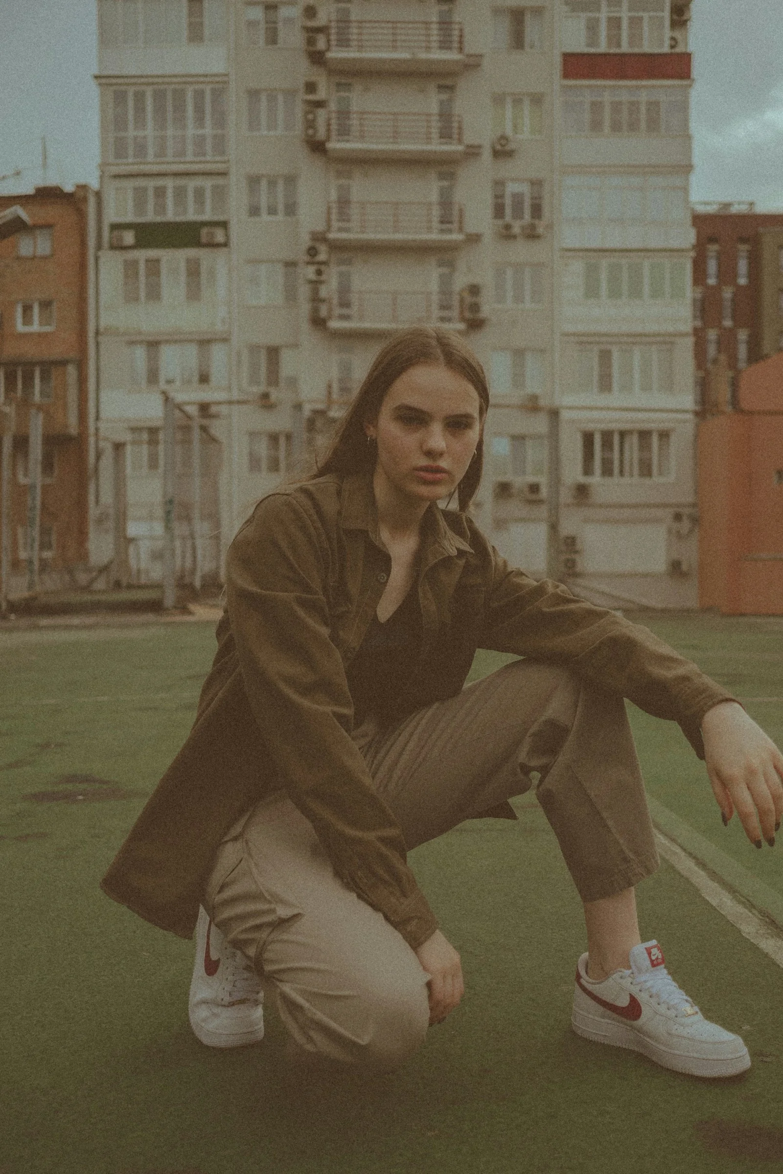 woman in brown coat sitting on green grass field during daytime