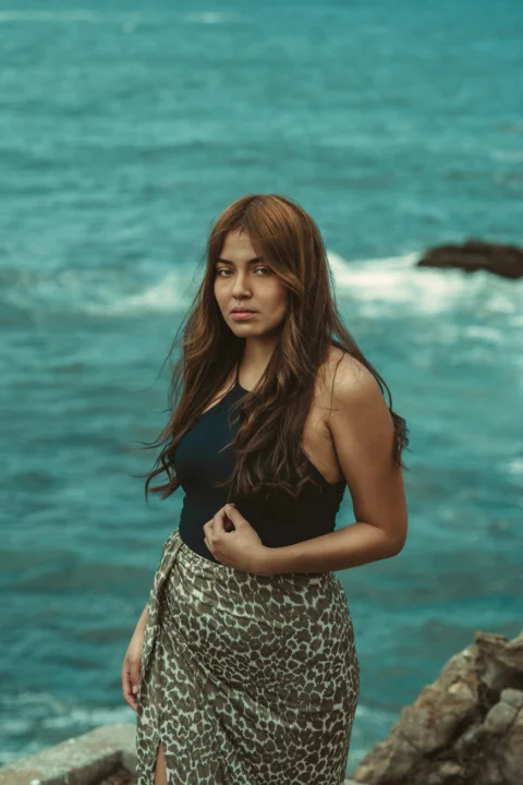 a woman standing on a rock next to the ocean