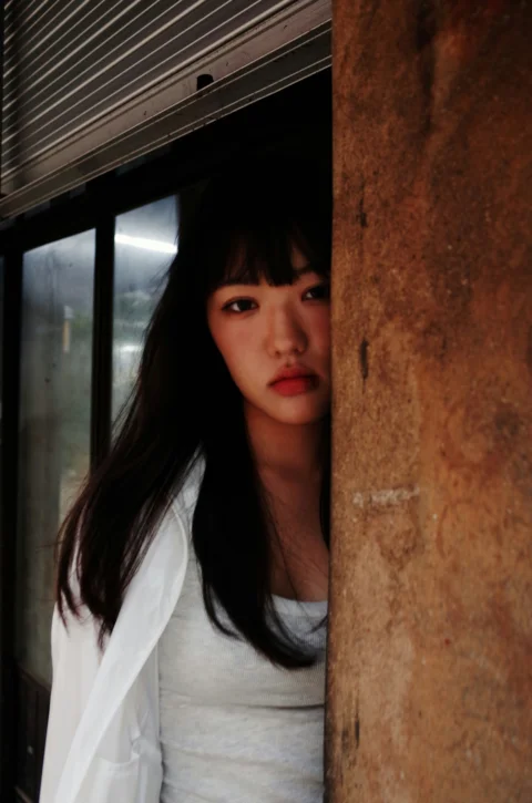 一个女人站在墙后看着镜头