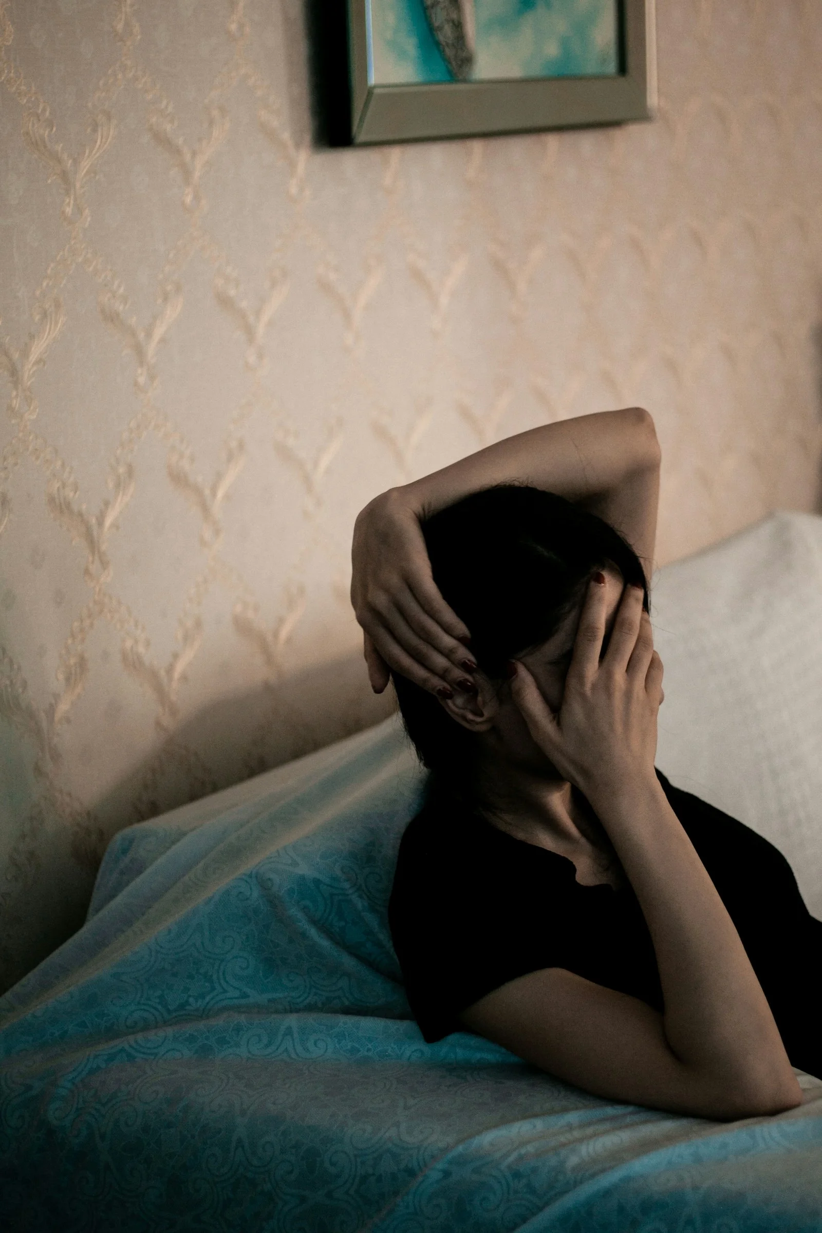 검은 셔츠를 입은 여성이 파란 담요로 얼굴을 가리고 있음