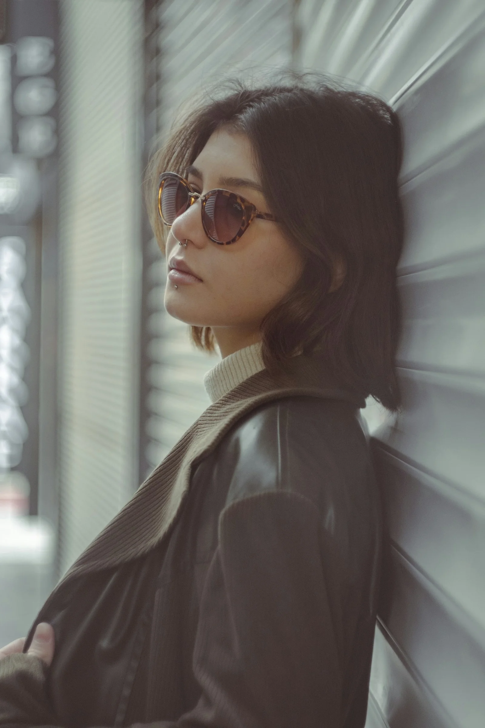 a woman wearing sunglasses leaning against a wall