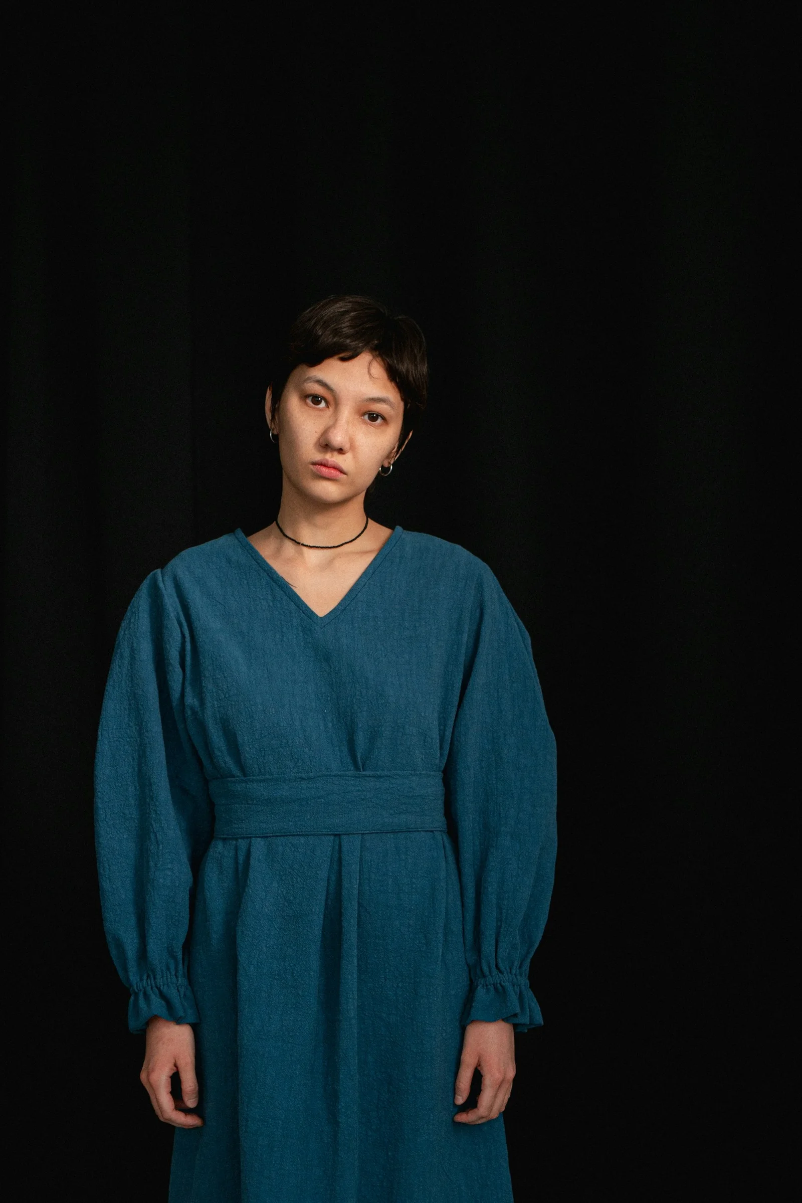 a woman in a blue dress standing in front of a black background