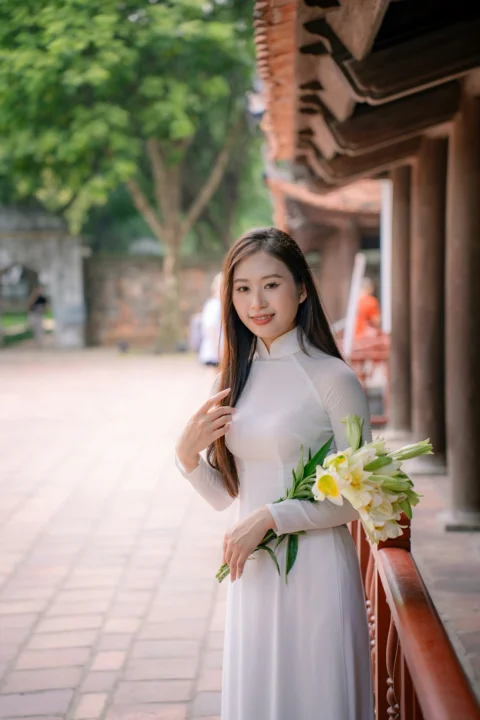 一名白衣女子带着鲜花摆姿势