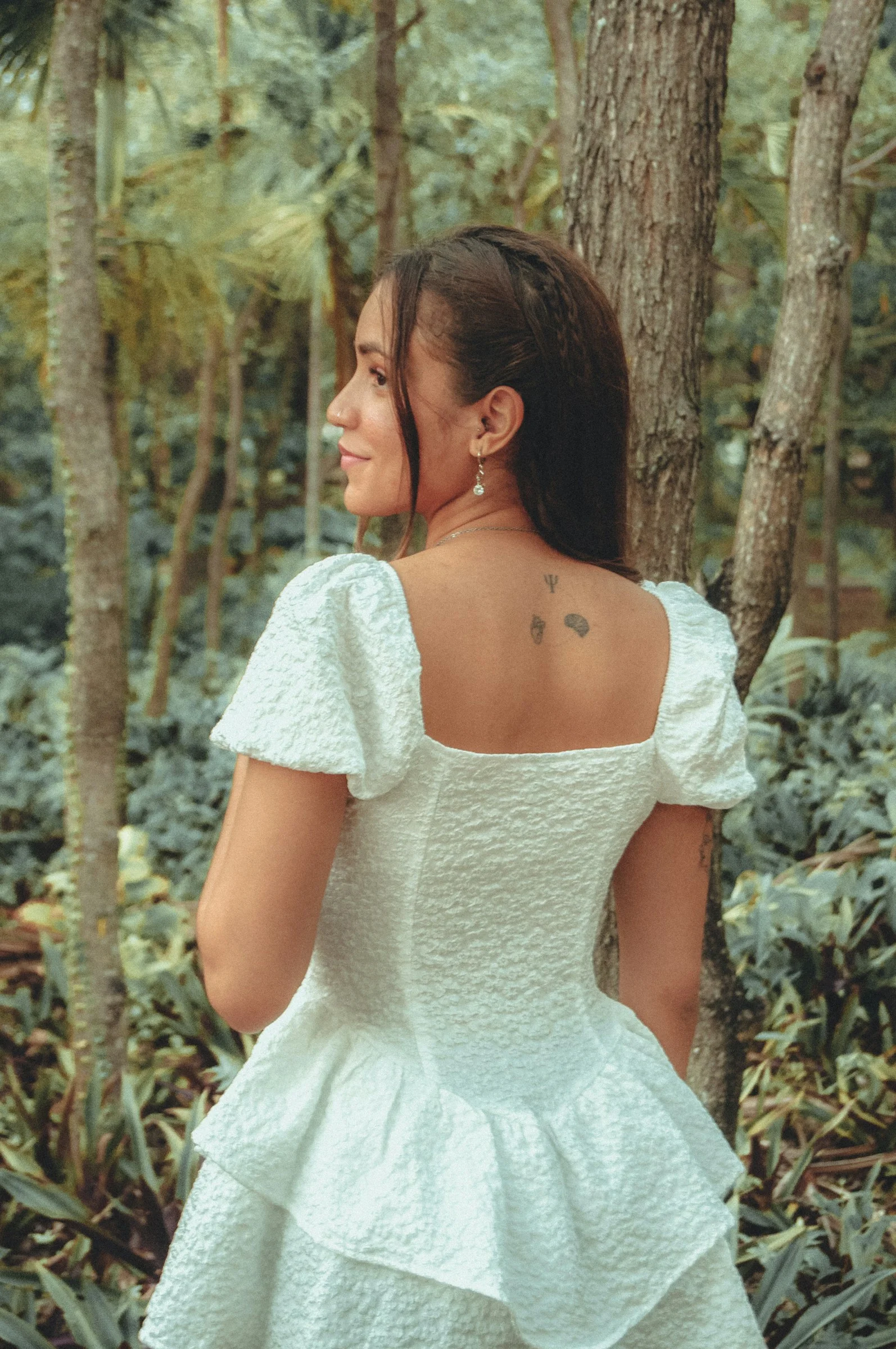 a woman in a white dress standing in the woods