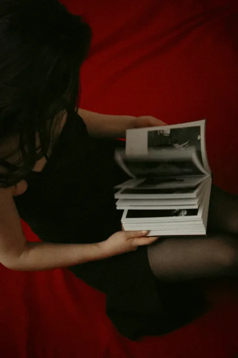 A woman in a black dress holding a stack of magazines