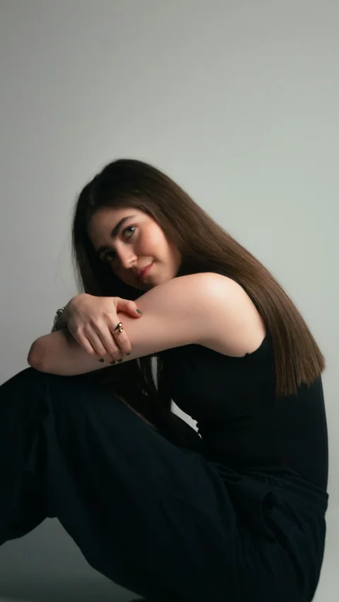 Young woman in black sitting, looking at the camera