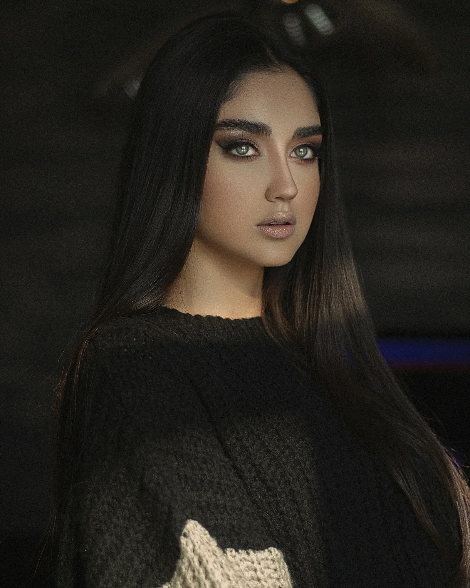 a woman with long black hair wearing a sweater