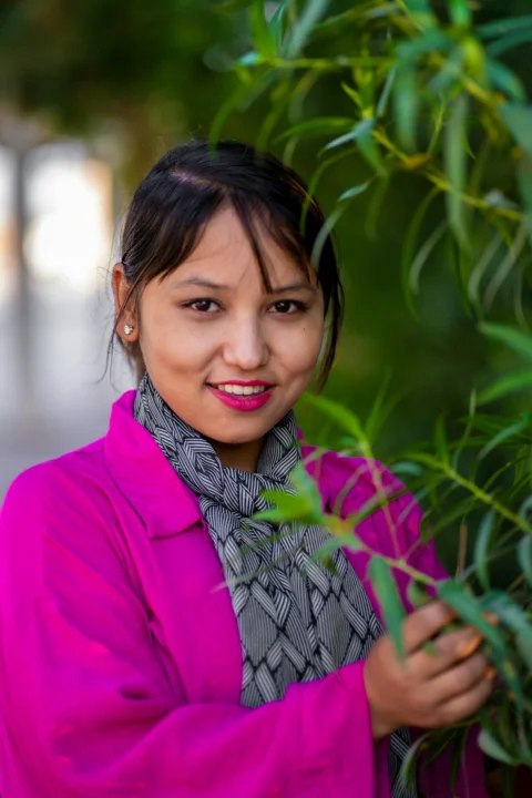 A woman standing next to a tree with a scarf on