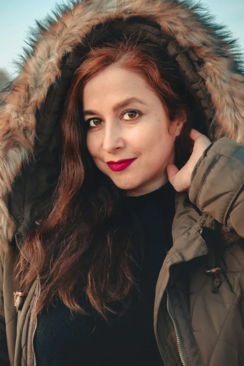 一位穿派克大衣的女人正在擺姿勢拍照