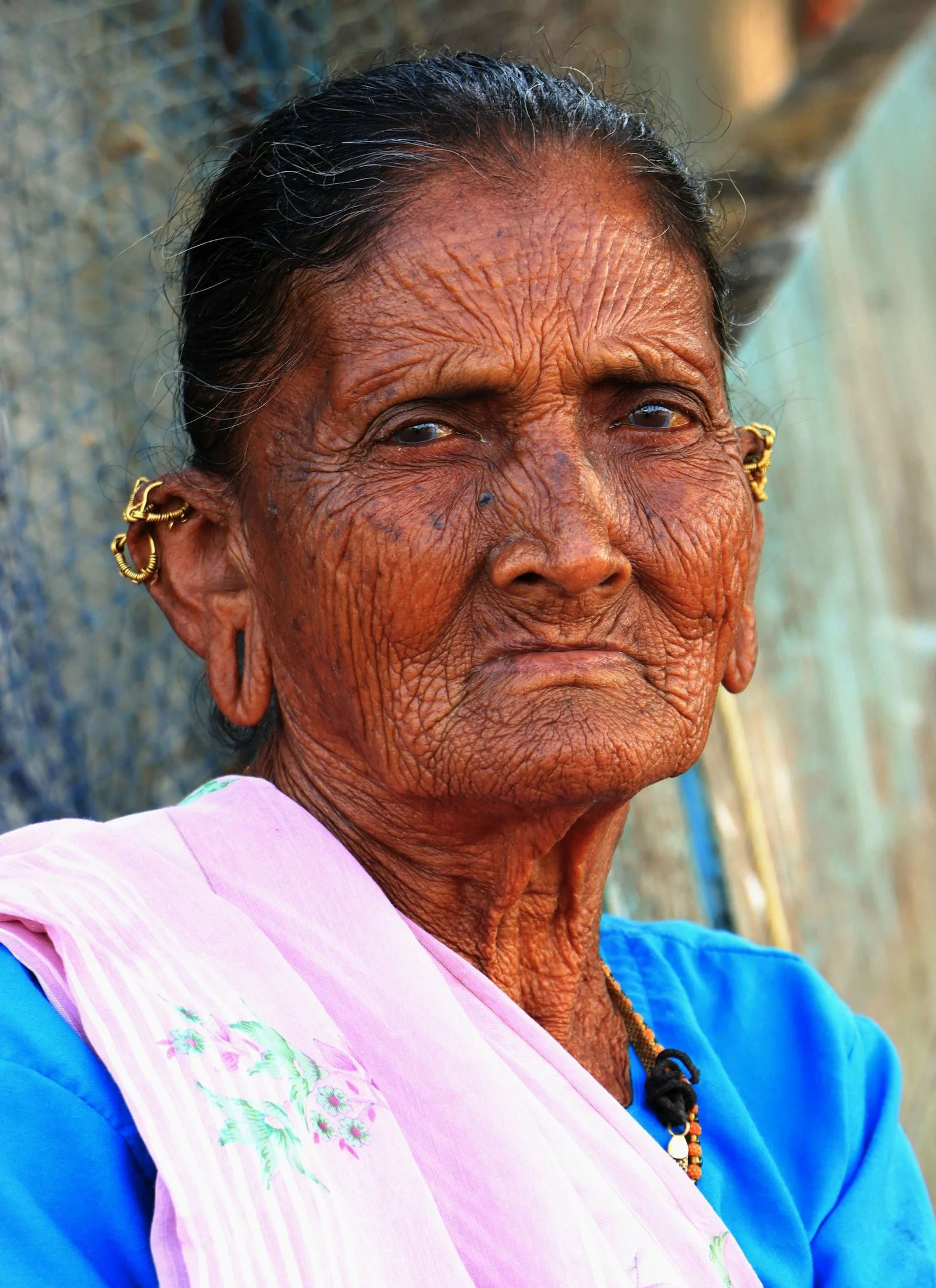 Elderly woman with wrinkled skin and gold earrings