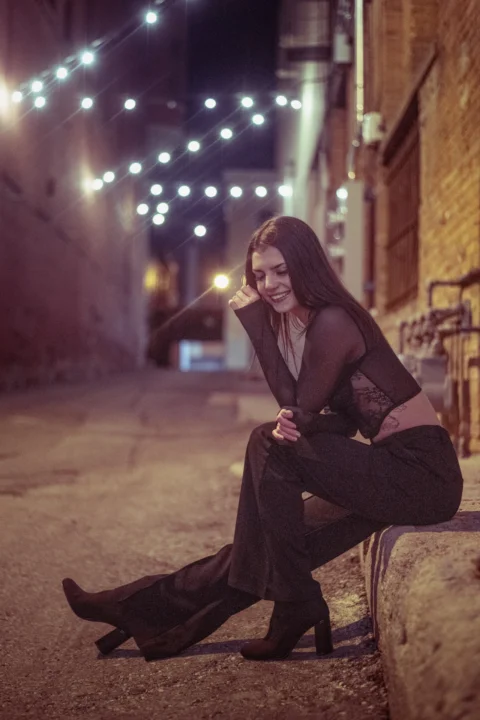 a woman sitting on a wall with a lit candle in her hand