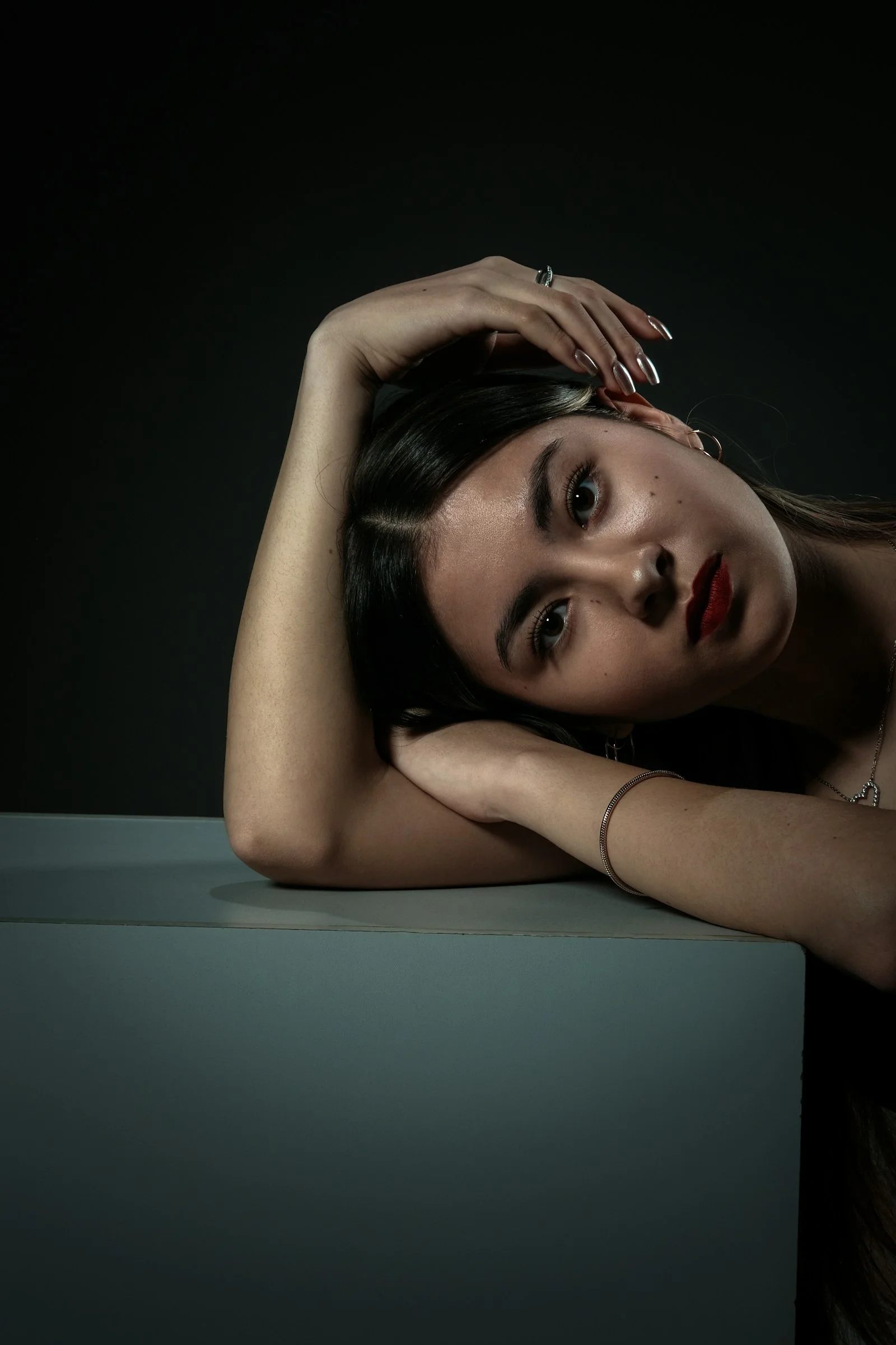 A woman poses with her arms on a cube