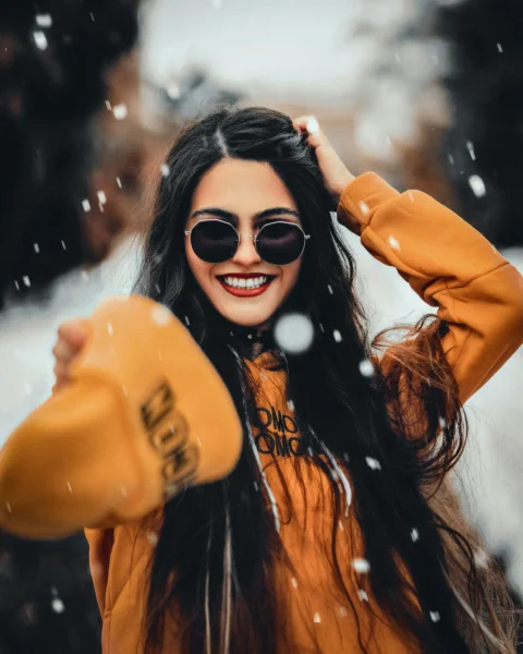 a woman wearing sunglasses and a hat in the snow