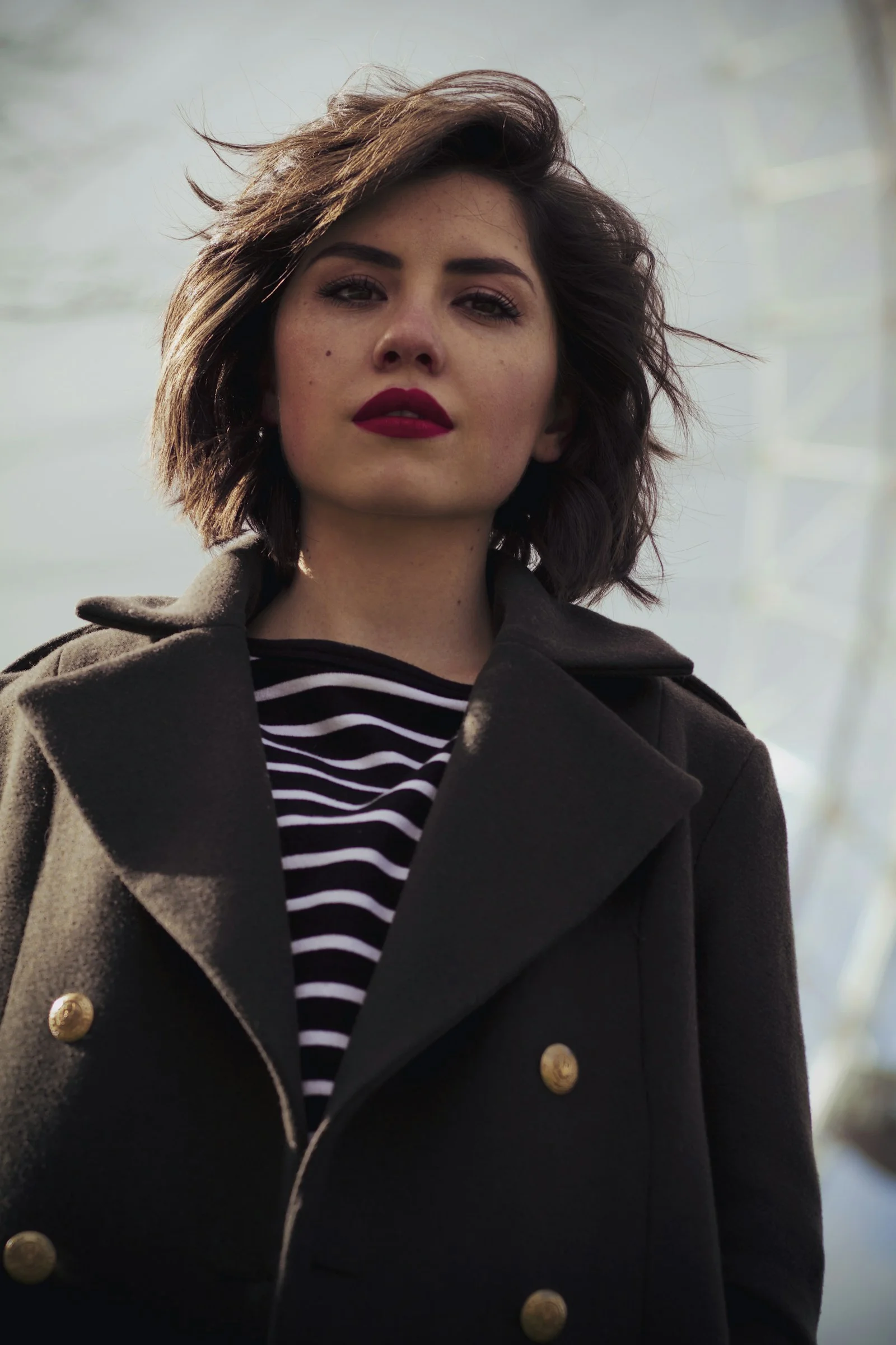 A woman wearing a coat and a striped shirt
