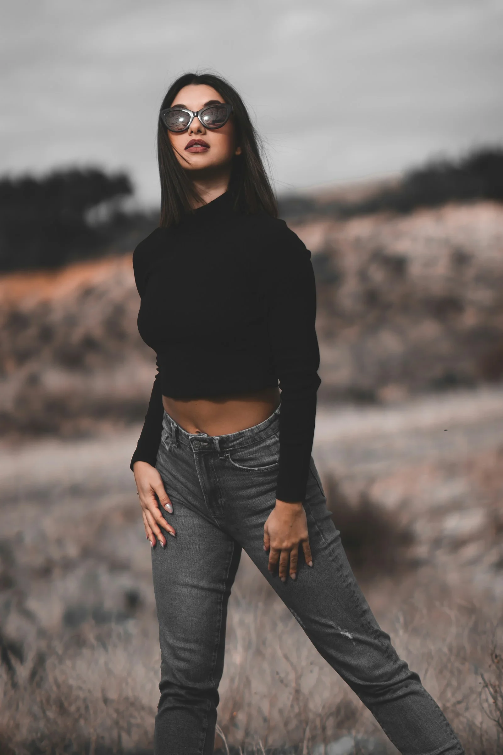 a woman standing in a field with her hands on her hips