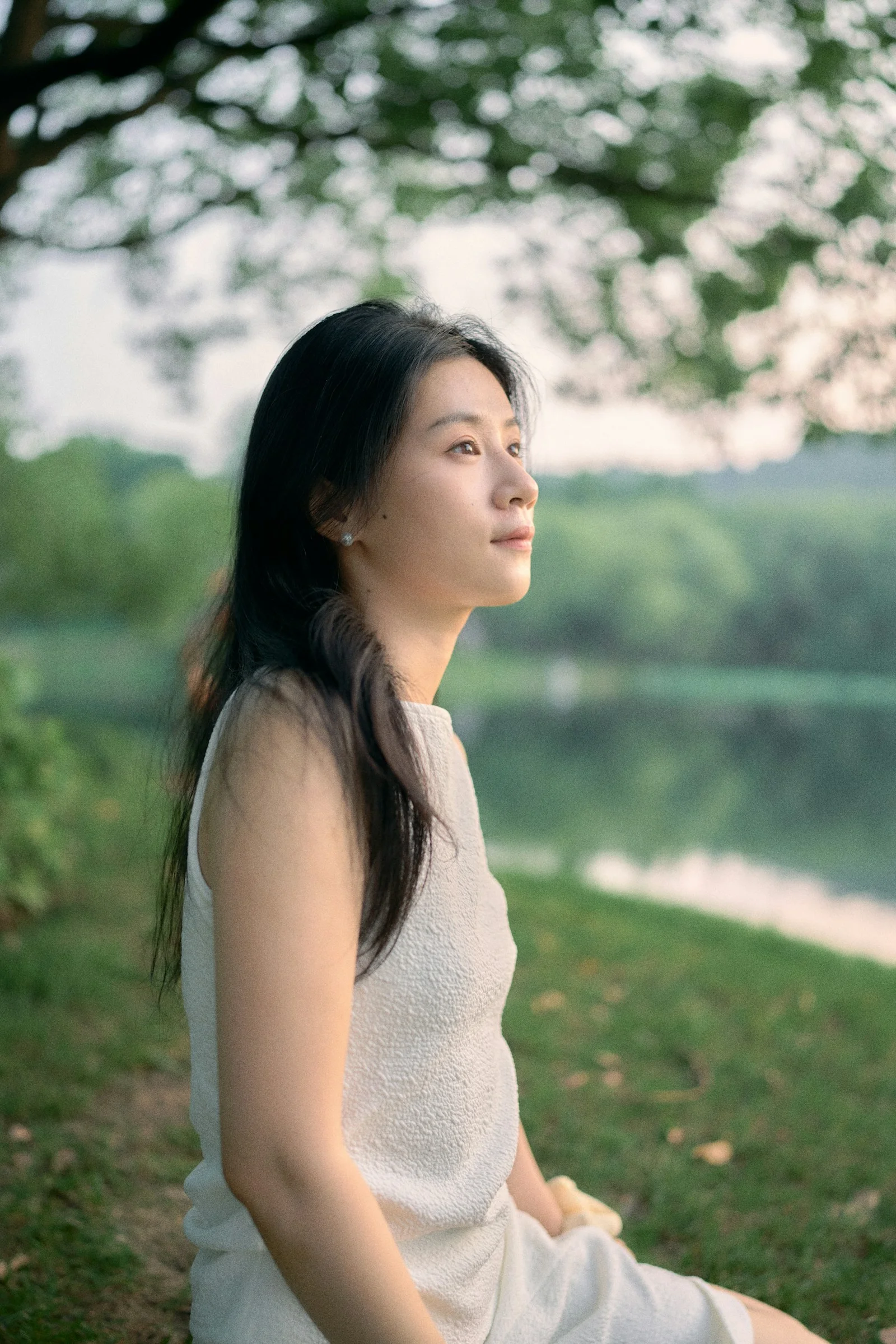 一位穿白色連身裙的女子坐在草地上
