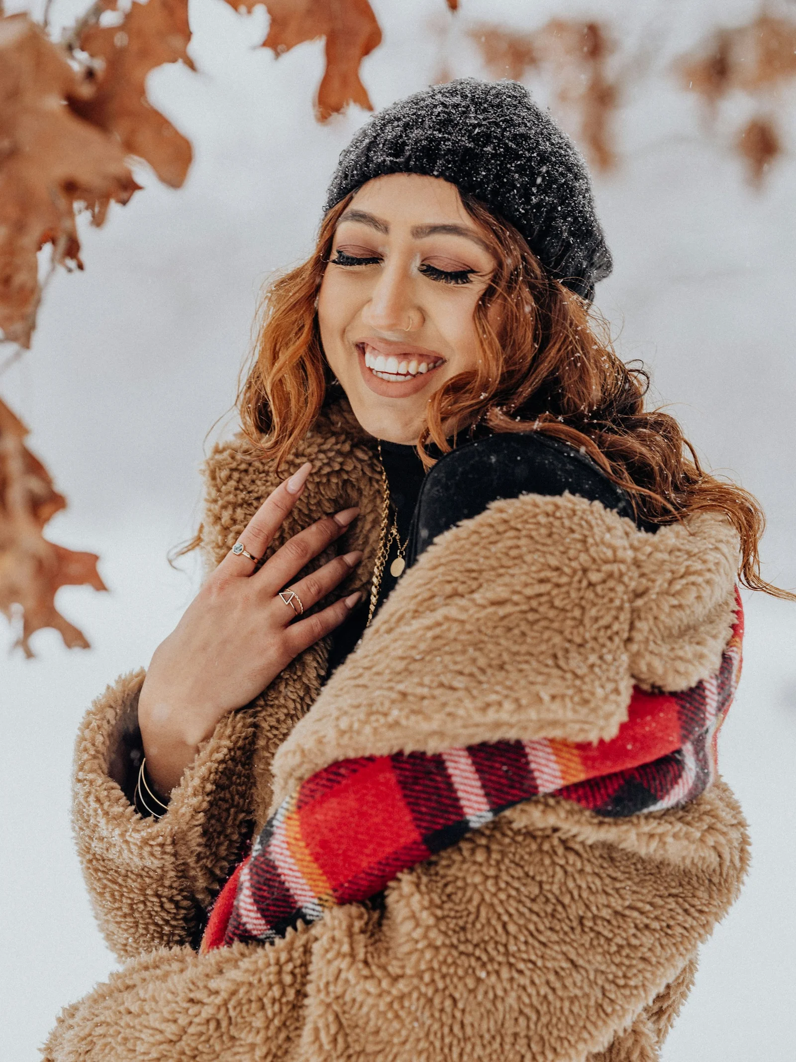 一个穿着夹克戴着帽子站在雪中的女人