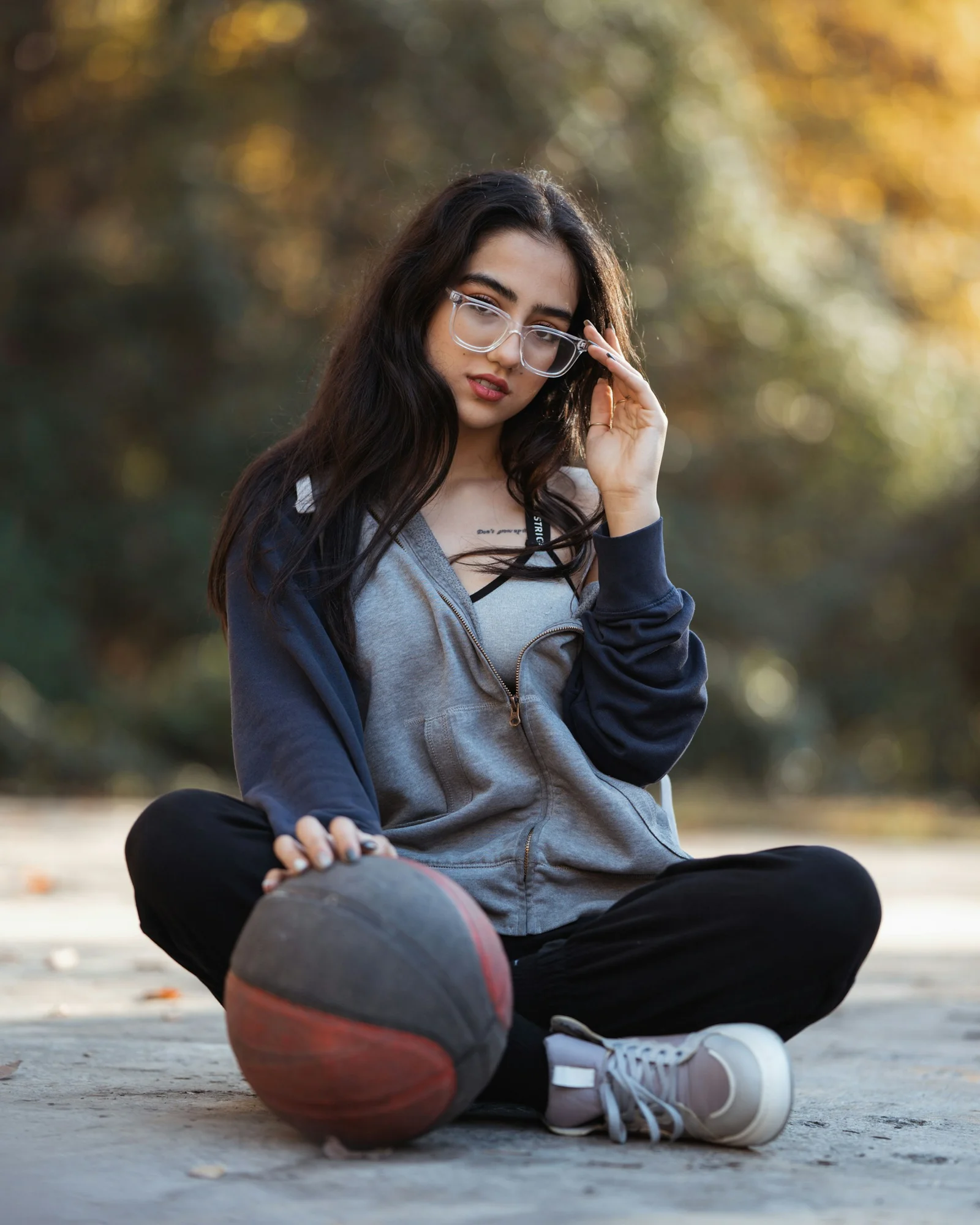 Young woman sits with basketball and glasses