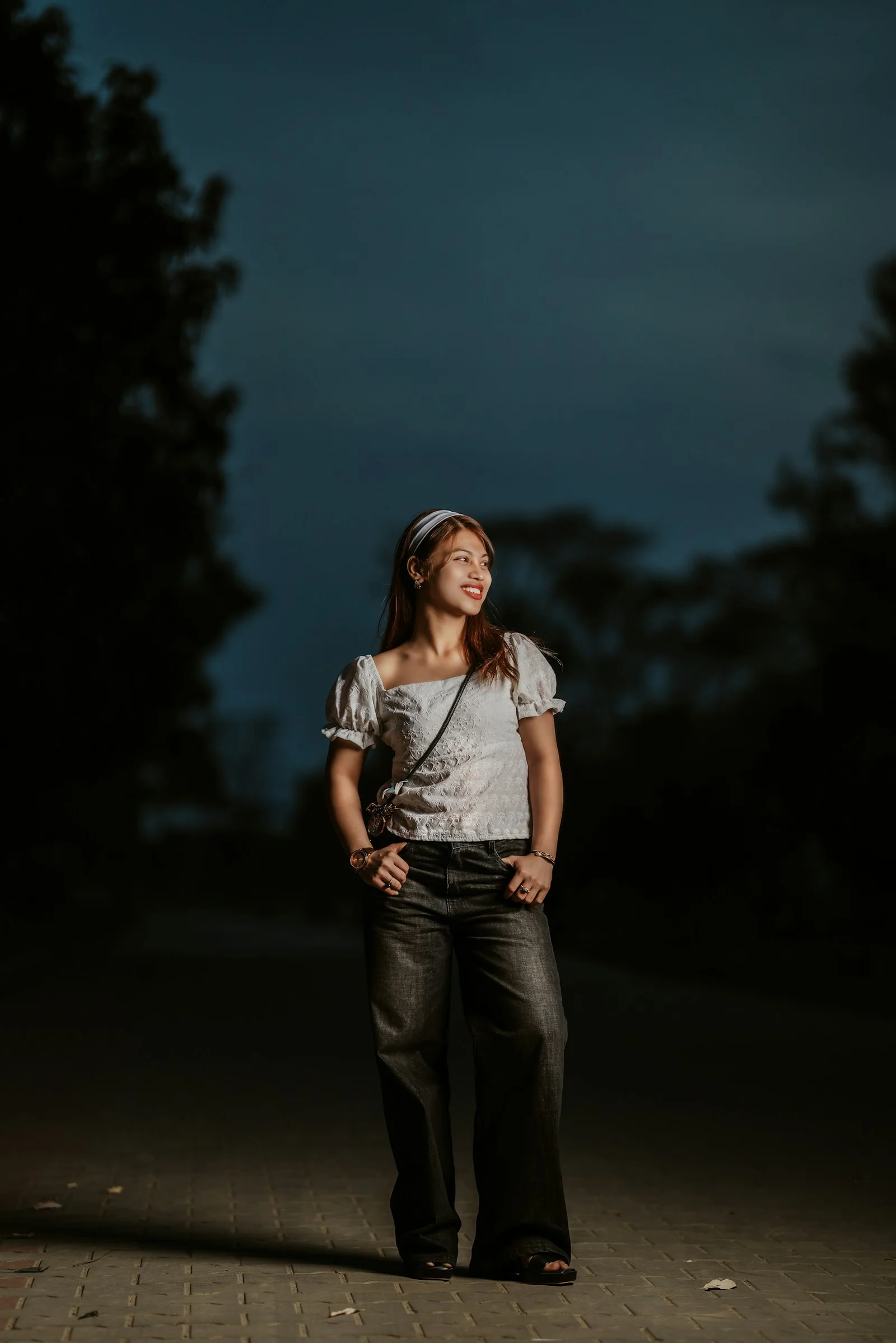 a woman standing in the dark with her hands on her hips