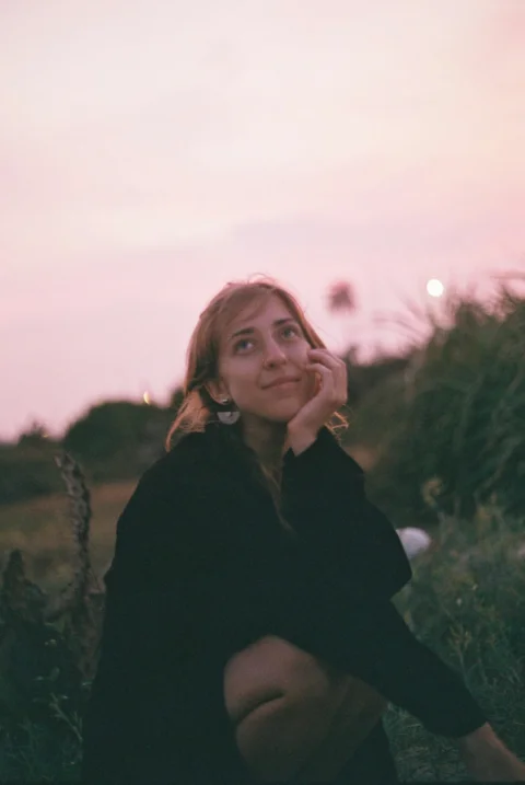 a woman sitting on the ground with her hand under her chin