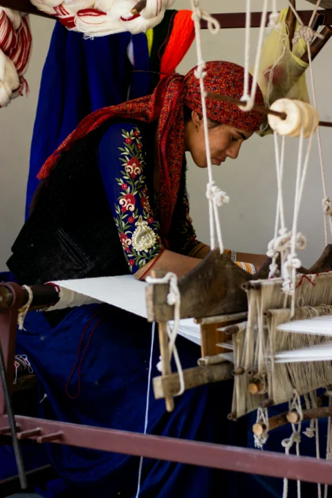 A woman is working on a weaving machine