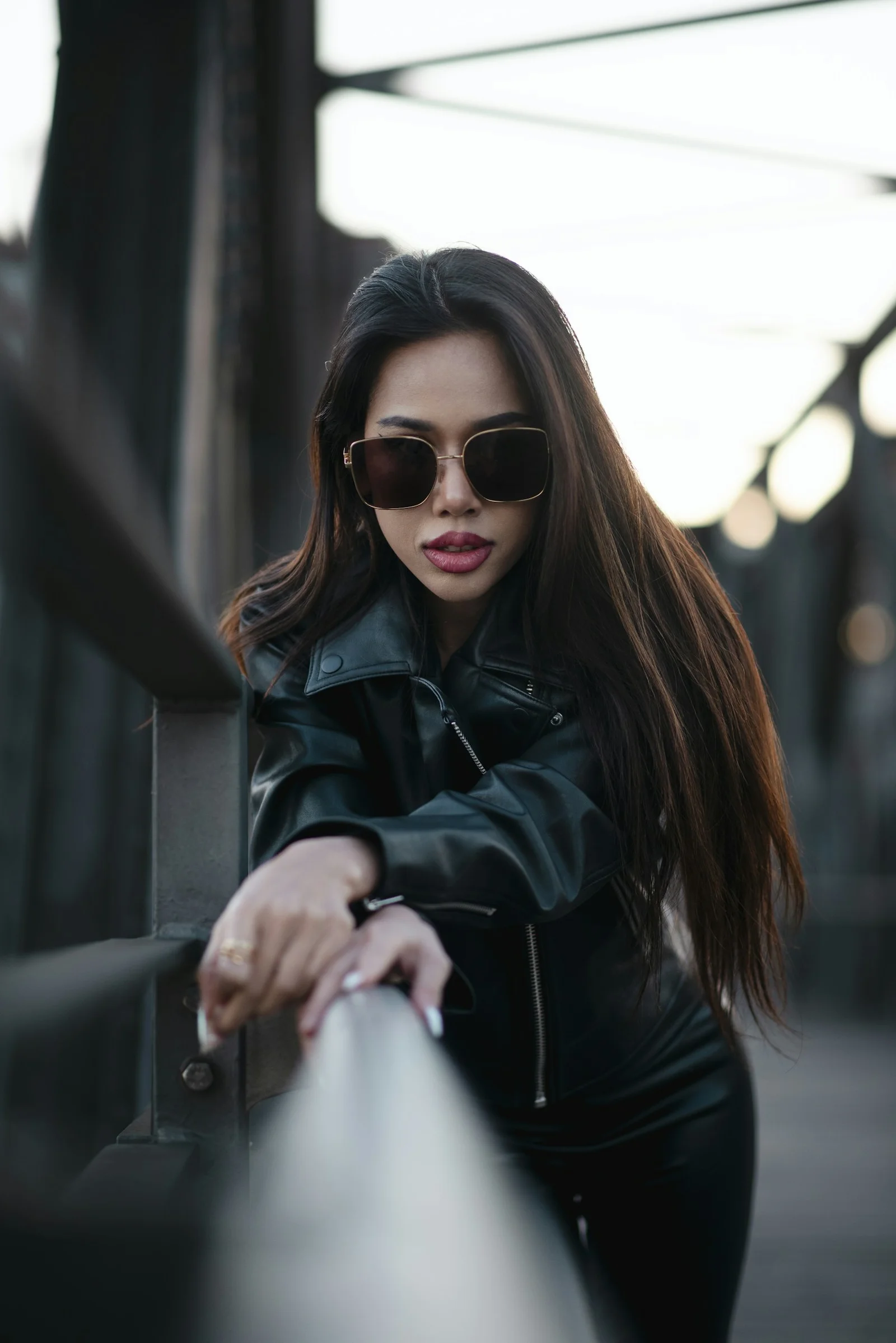 Woman posing confidently in sunglasses and a leather jacket